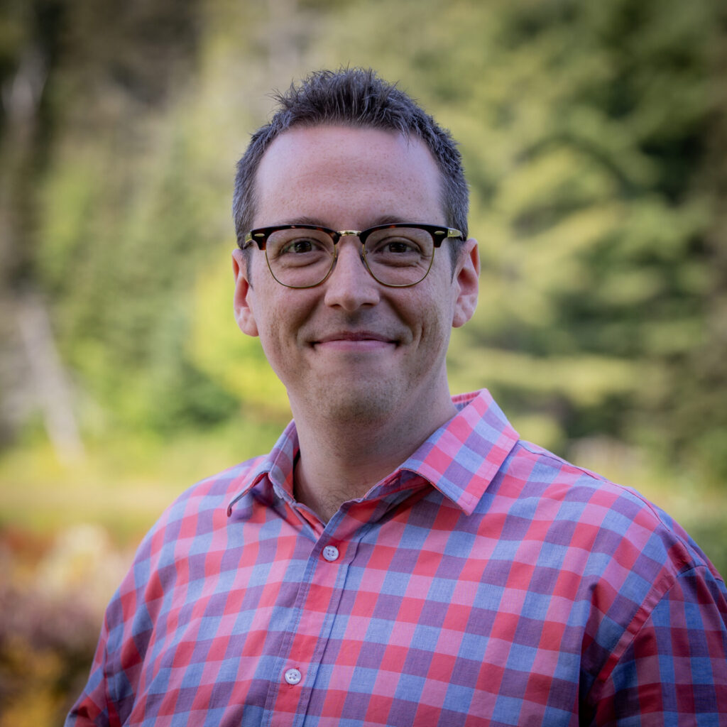 A man in checkered shirt in front of a blurred nature background