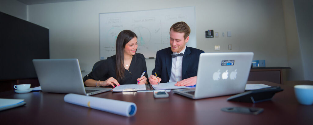 2 students in business attires working with their laptops on the table