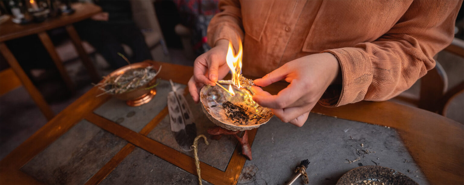 A close up of someone's hands burning up an indigenous item