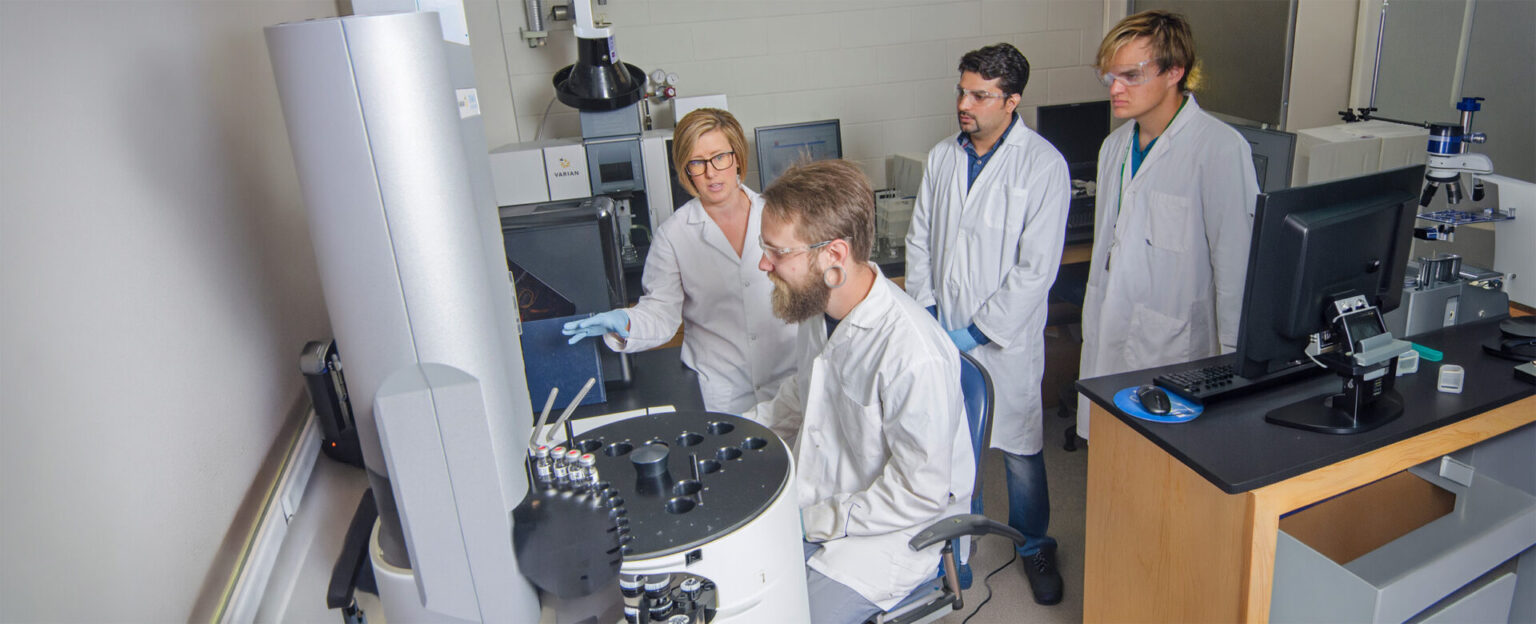 A group of people in white lab coats working on a machine