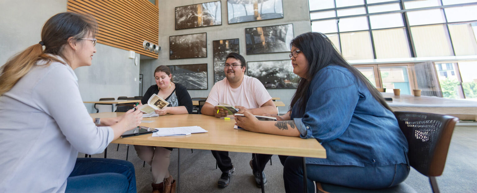 4 students sitting at a table working at a open space in the library