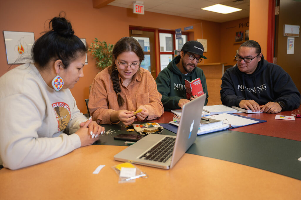 4 indigenous students sitting around the table with notebooks and laptops