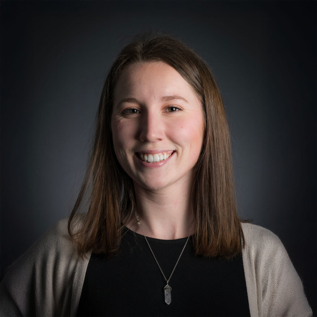 A woman in black shirt against a lit black background