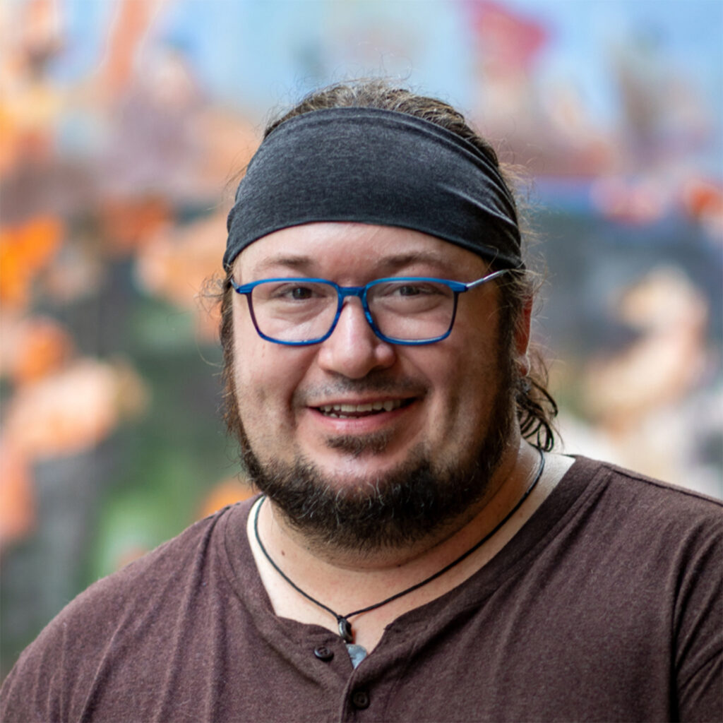 A man in glass and black hairband against a colorful blurred-out background