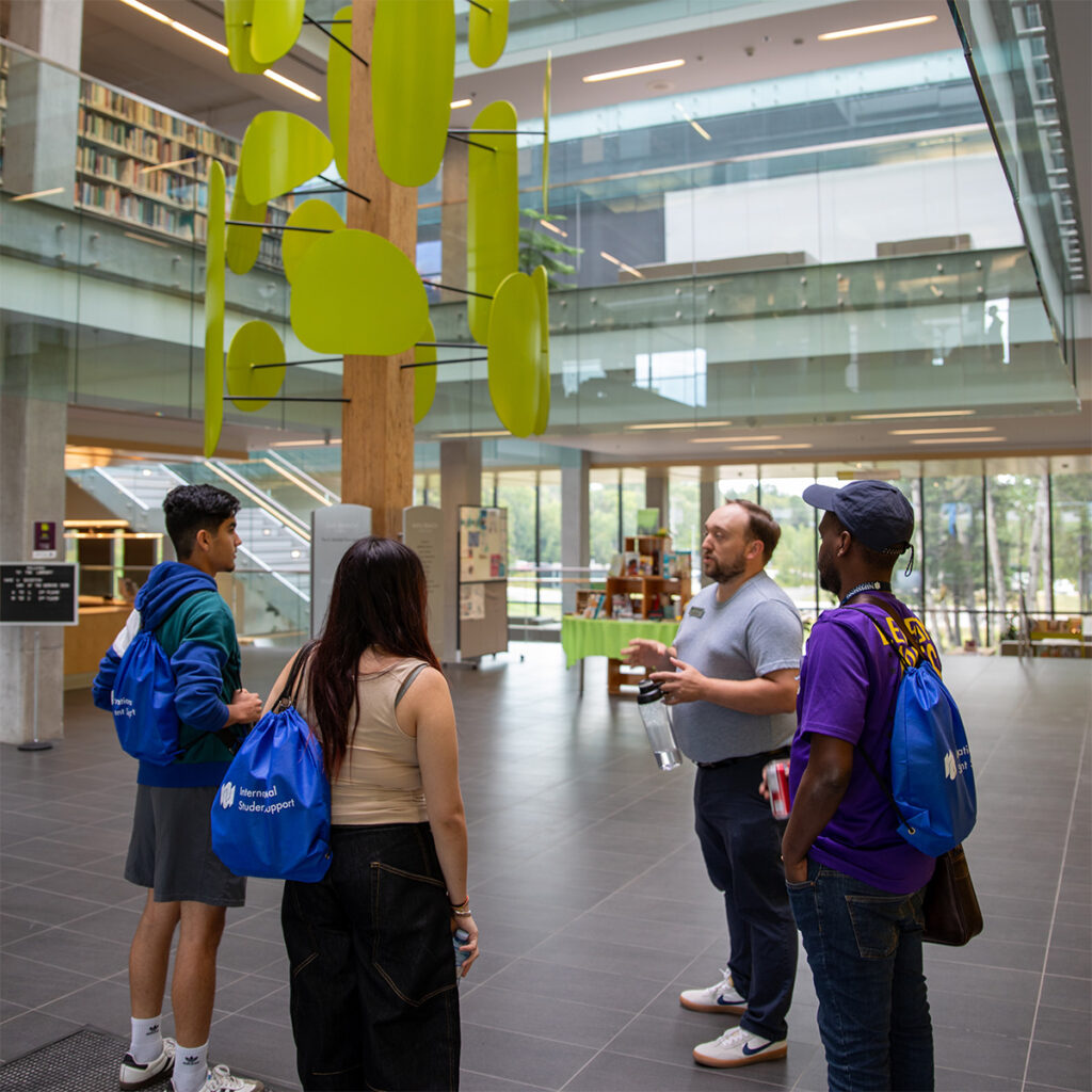 A staff and 3 students standing in the library