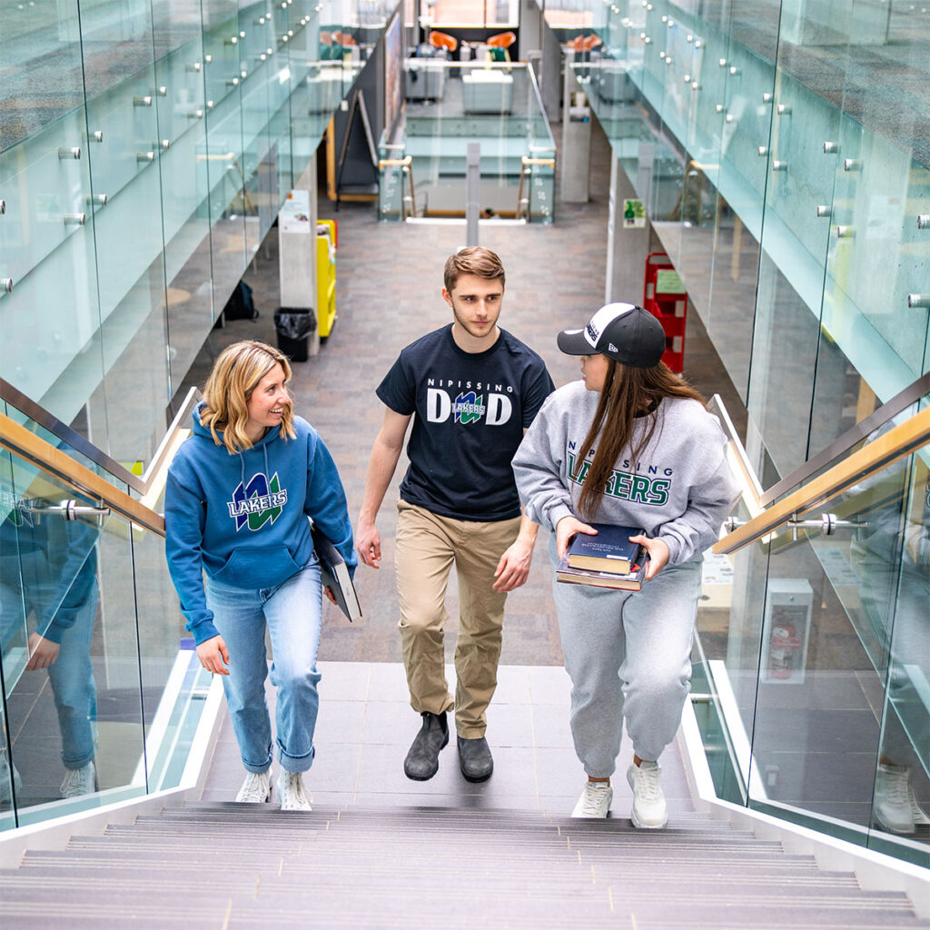 3 students walking up the stair in the library
