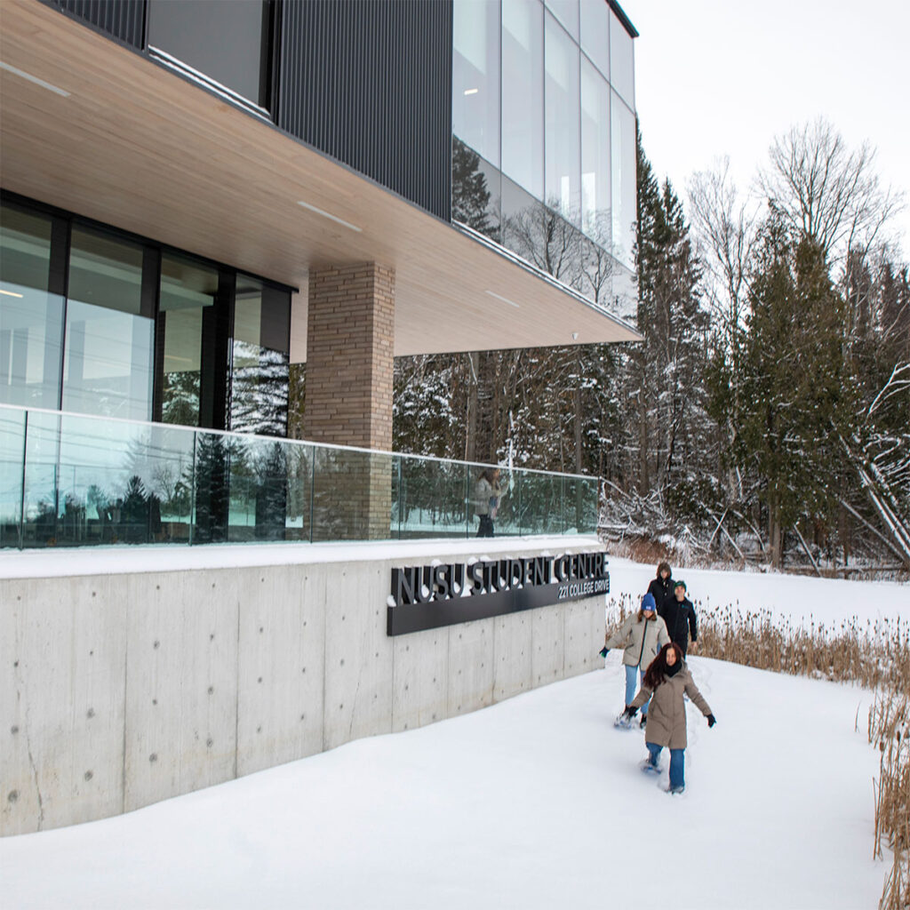 Some student treading through the snow in front of the student centre