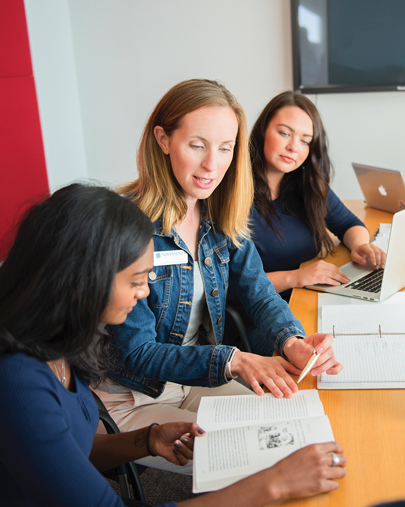 A staff member helping a student with some documents in an office setting